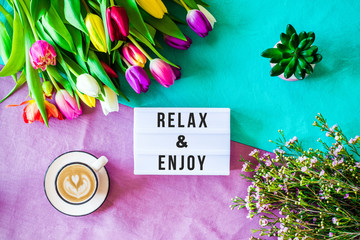  Relax & Enjoy written in lightbox with spring flowers from above