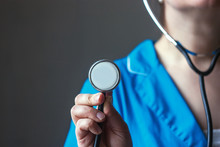 Doctor In Blue Uniform Holds A Stethoscope