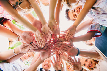 Close-up of happy people heaping hands in summer