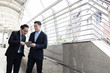 © khwanchai - Businessman presenting work to boss, leader about planning project by laptop outside building.