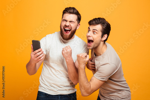 Fotomural Image of two bachelors screaming and rejoicing win of football team while watchi