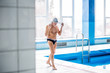 © Halfpoint - Senior man walking by the indoor swimming pool.