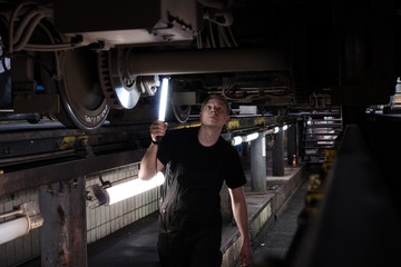 Mechanic using light to inspect a subway car