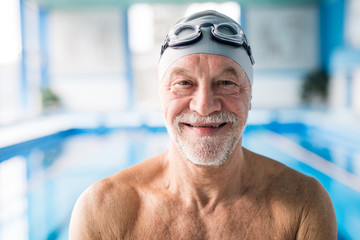 senior man standing in an indoor swimming pool.