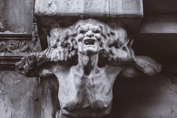 bust of concrete of a terrible woman on the facade of an old house