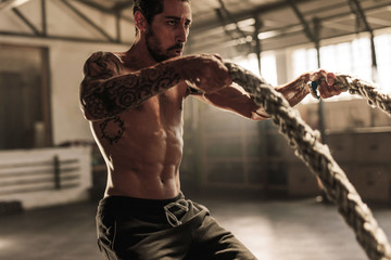 Wall Mural - Athlete working out with battle ropes at gym