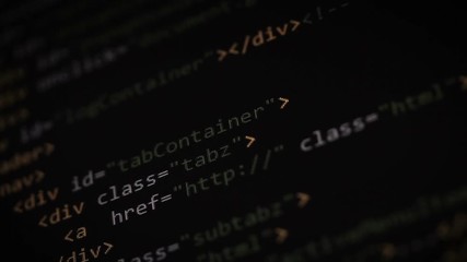 Website development. Closeup of HTML, CSS, JavaScript and PHP colorful code scrolling over dark background on computer screen