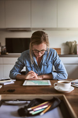 Wall Mural - Young female entrepreneur working online with a tablet at home