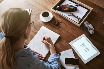 Wall Mural - Female entrepreneur sketching on a notepad in her home office