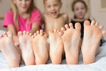 Happy Brother And Sisters  Sitting On The Bed Barefoot