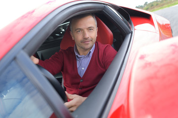 man sits in red lamborghini on race track