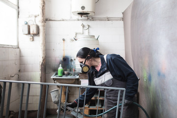 Wall Mural - Strong and worthy woman doing hard job. She using industrial spray compressor for painting some metal products.