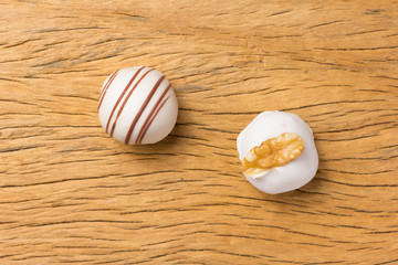 Homemade white chocolate truffle. Overhead of candy ball on rustic wood table.