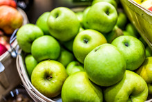 Closeup Of Many Granny Smith Green Yellow Apples In Wooden Basket At Farmer's Market Shop Store Showing Detail And Texture