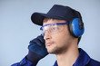 © Africa Studio - Male worker with headphones on grey background. Hearing protection equipment