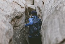 Rear View Of Female Hiker With Backpack Canyoneering Amidst Narrow Canyons