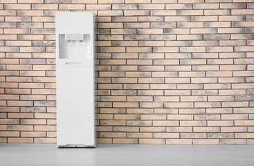 Modern water cooler near brick wall