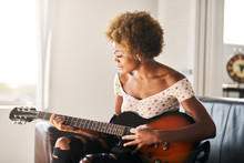 African American Woman Playing Guitar At Home