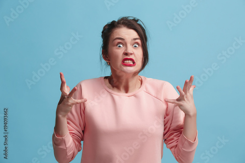 Fotomural Portrait of an angry woman looking at camera isolated on a blue background