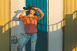 © tinyakov - Young Beautiful Girl Stands Near Colorful Wall With Binoculars In Hand And Staring Into The Distance. Scout Travel Concept