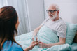 Nurse giving old man in bed a glass of water