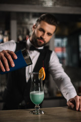 Wall Mural - handsome bartender preparing alcohol cocktail