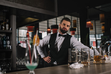 Wall Mural - tired bartender leaning on bar counter and looking at dirty glasses and trash