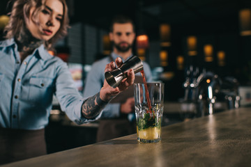 Wall Mural - bartender adding ingredient to alcohol drink at bar