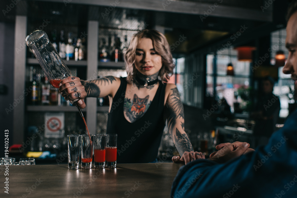 tattooed bartender making shot drinks for visitor at bar - obrazy, fototapety, plakaty 