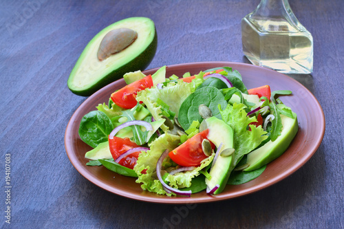 Fotografie, Obraz Green tossed salad with leafy vegetables, arugula, baby spinach, avocado, cherry tomatoes and pumpkin seeds