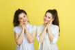 © Alexandr - two beautiful joyful sisters twin girls in white blouses on a yellow background