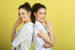 © Alexandr - two beautiful joyful sisters twin girls in white blouses on a yellow background