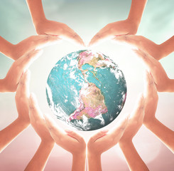 Wall Mural - Earth Day concept: Heart shape of hands holding earth globe over blurred nature background. Elements of this image furnished by NASA