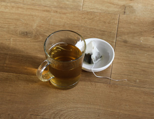 Glass of green tea with tea bag on wooden background