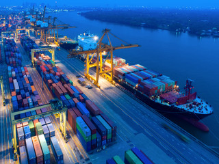 Aerial view of Containers yard in port congestion with ship vessels are loading and discharging operations of the transportation in international port.Shot from drone.