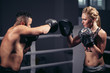 girl training on boxing mitts held by master boxer
