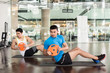 © Kzenon - Full length side view of a determined young man holding a weight plate, while exercising Russian twist for core and oblique abdominal muscles at the gym