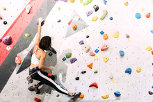 Woman Practicing Rock Climbing On Artificial Wall Indoors.