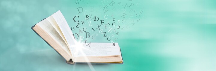 Wall Mural - opened book with light and letters on green background