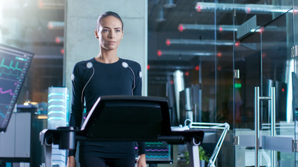 Wall Mural - beautiful woman athlete with electrodes connected to her body walks on a treadmill in a sports scien