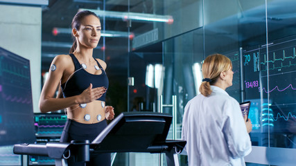 Wall Mural - beautiful woman athlete runs on a treadmill with electrodes attached to her body, female physician u