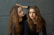 © Alexandr - portrait of two beautiful young girls of twin sisters with flowing hair against the gray wall in the interior