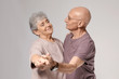 © Africa Studio - Cute elderly couple dancing against grey background