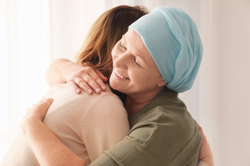 woman hugging her mother with cancer indoors