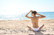 © vitaliymateha - beautiful sexual young woman in white bikini sits on the beach against the sea and sky at sunny day. happy woman enjoys summer vacation and sunbathing. Back view