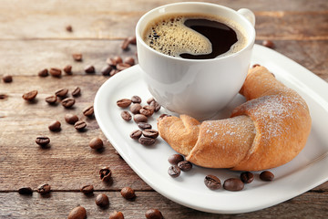 Sticker - Tasty crescent roll and cup of coffee on wooden background