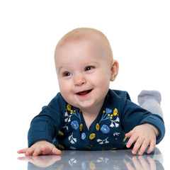 A cute, very little girl is lying on the floor on a white backgr