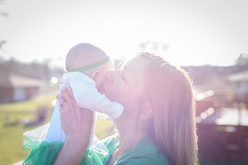 mother holding baby up in bright sunlight