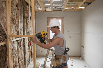 young builder industry trainee man on his 20s wearing protective helmet learning working with drill at industrial workshop site