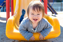 Mixed Race Toddler Boy Playing On A Slide At A Playground